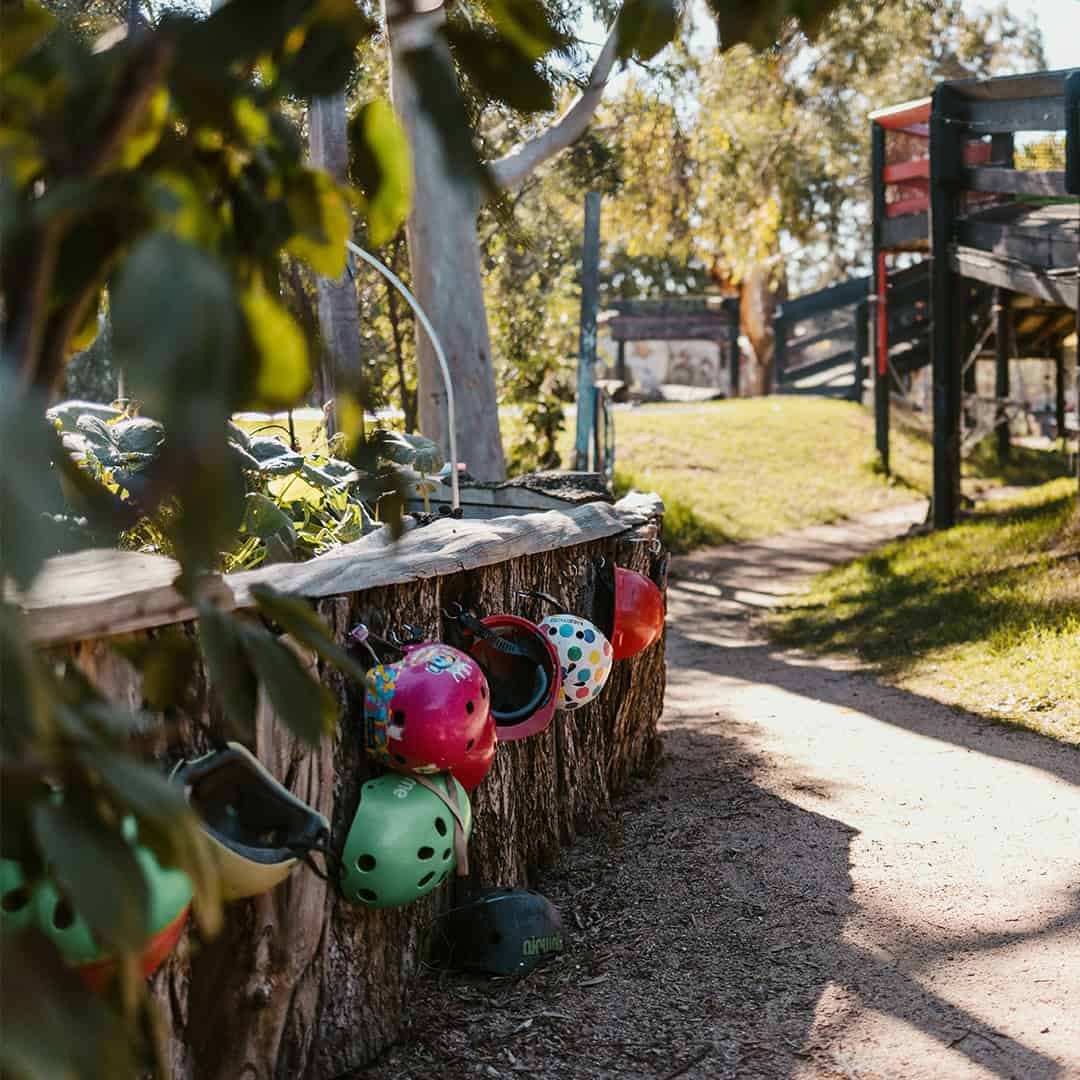 Play Area at The Venny Community Garden Children's helmets hanging on a wooden fence in The Venny community garden.