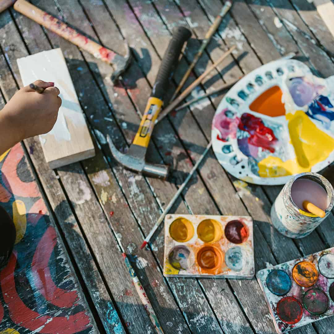 Creative children’s art activity at The Venny community space. Colorful paint palette and brushes on wooden table for kids' art projects.