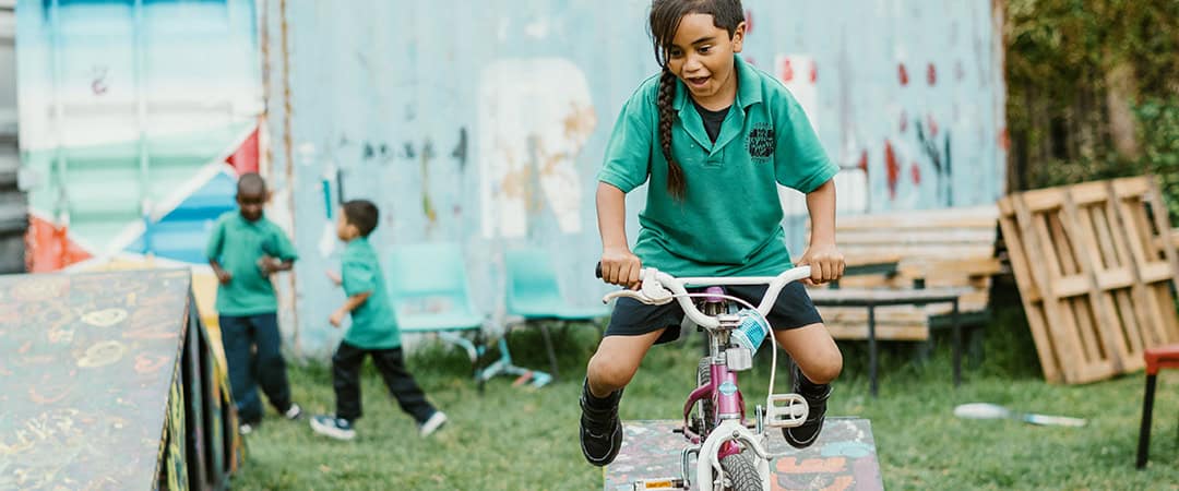 Venny girl riding a pink bicycle at The Venny community farm.