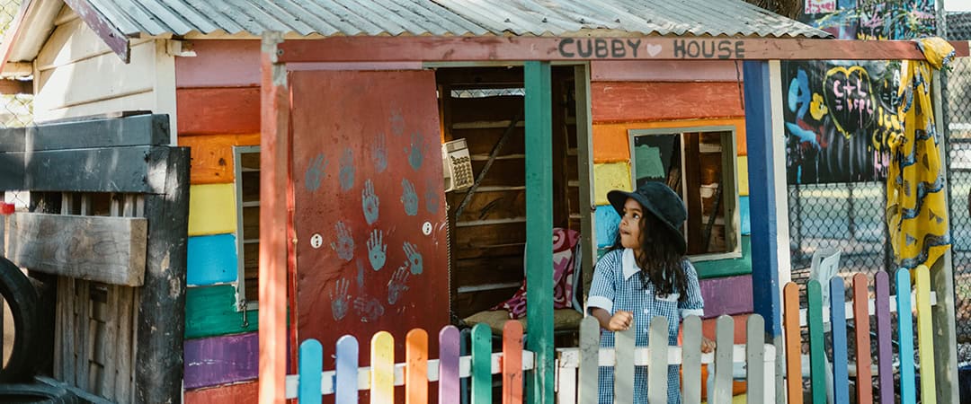 The Venny Cubby House Venny outdoor cubby house with colorful painted walls and a young girl playing outside.