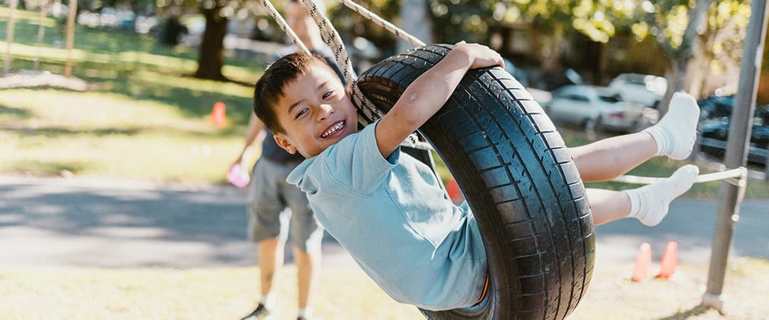 Children playing on tire swings at The Venny community farm and play space.