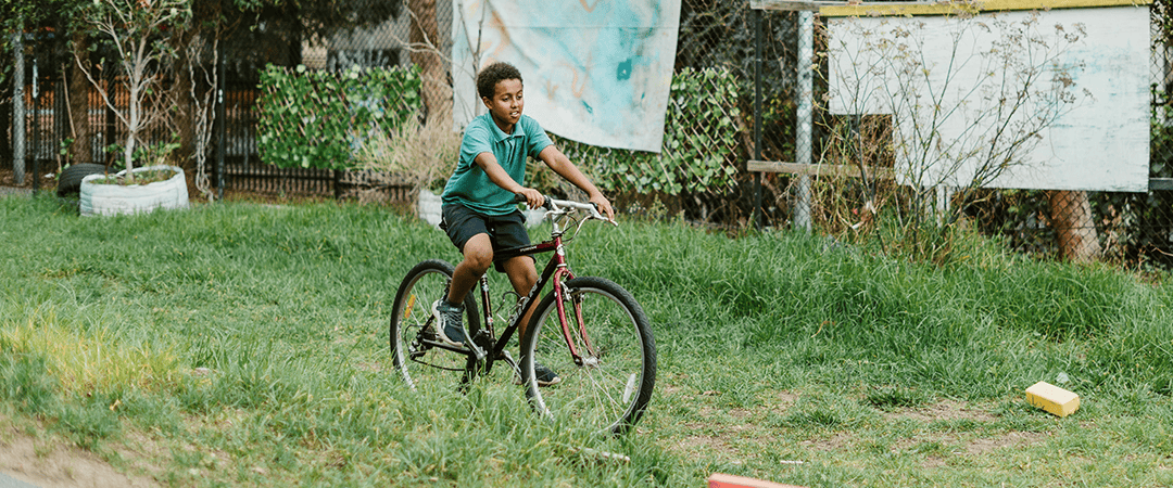 The Venny outdoor community space with children playing. Child riding a bicycle in The Venny community garden.